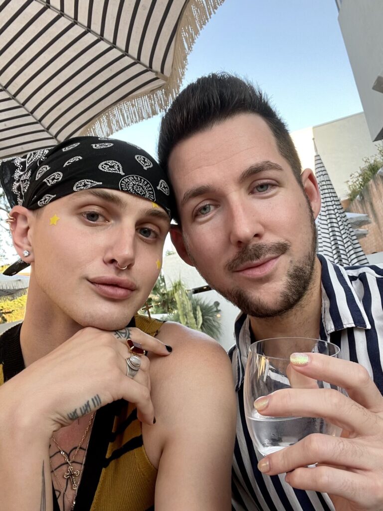 Kyle and their fiance while wearing a bandana and drinking wine.