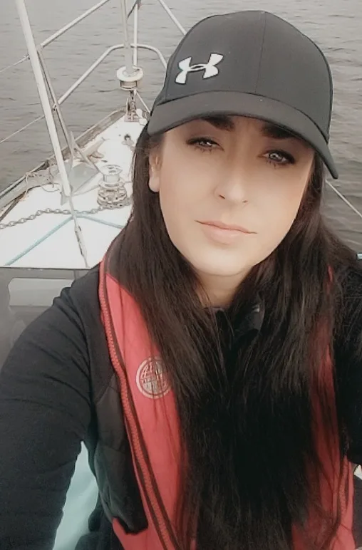 Ceira can be seen on a boat while wearing a black cap and red life jacket.