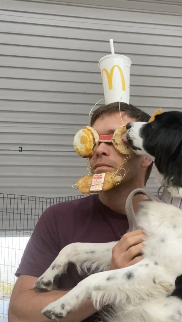 Jack is shown with McMuffin shades and a hash brown on his chin as a dog licks him. 