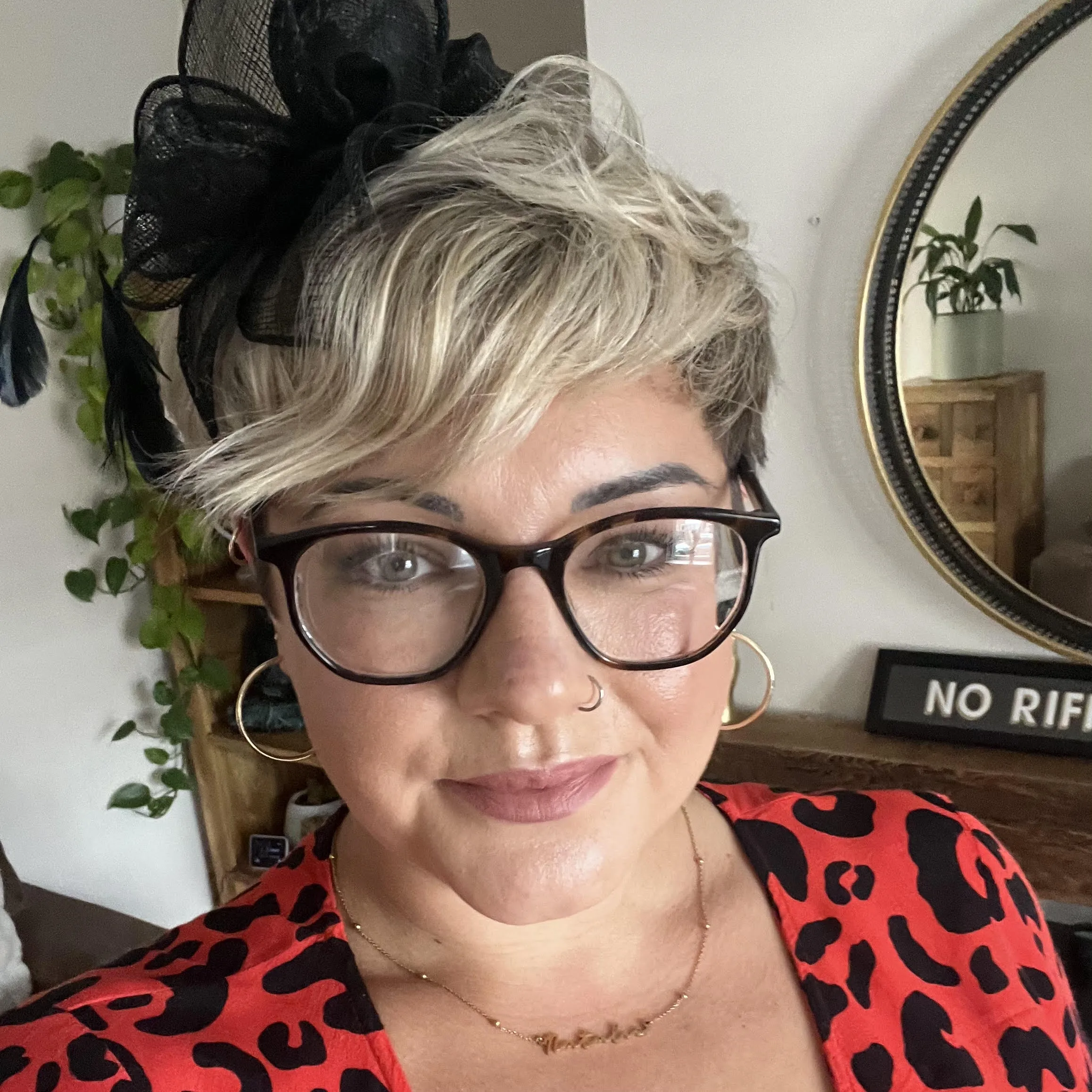 Natalie smiles while wearing a red and black spotty dress and black hair clip.