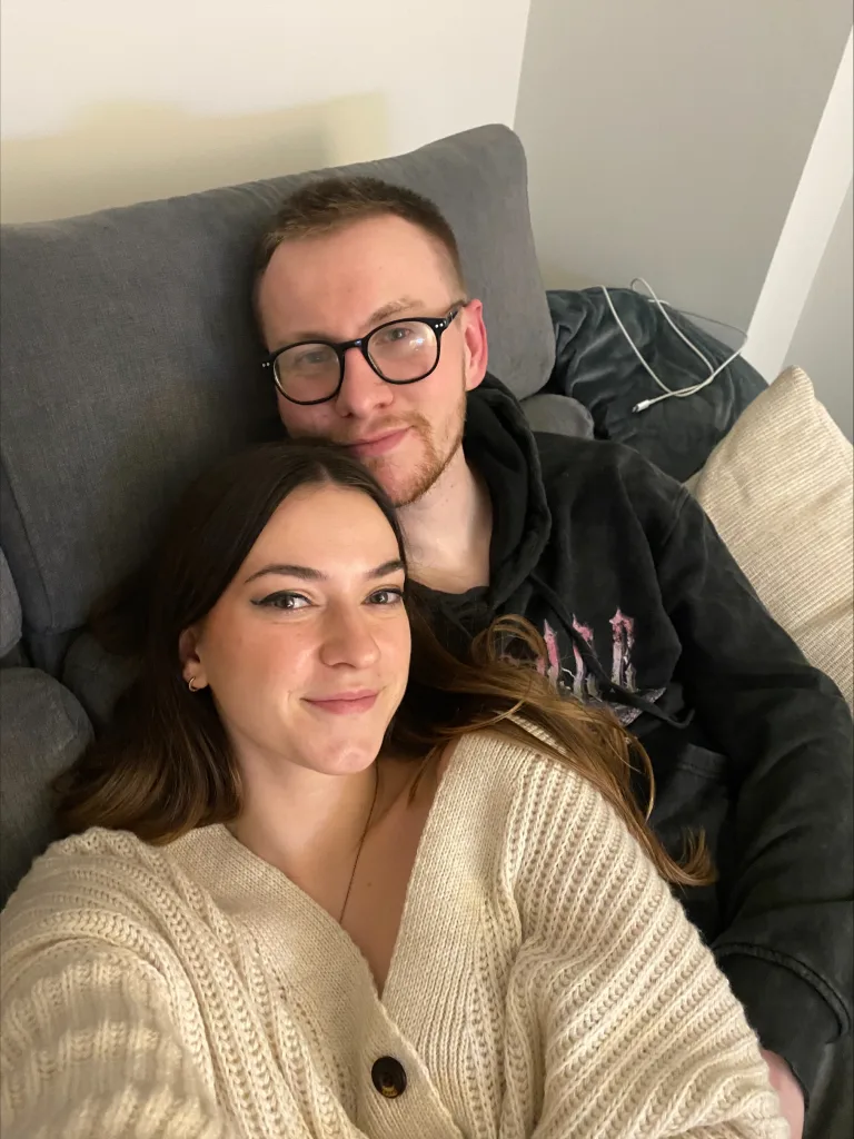 Olivia and her partner are pictured smiling while on the sofa. 