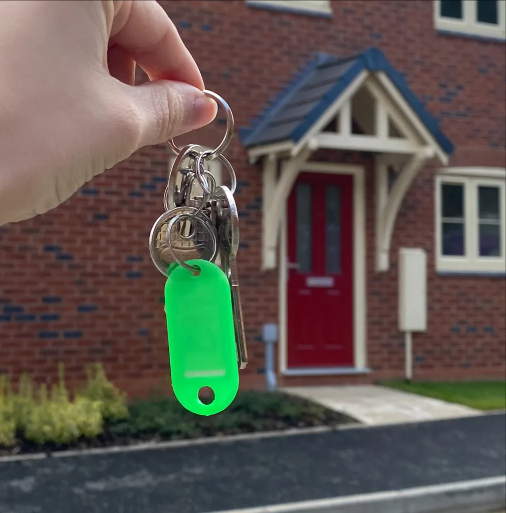 Olivia's hand is pictured holding up the keys with her home in the background. 