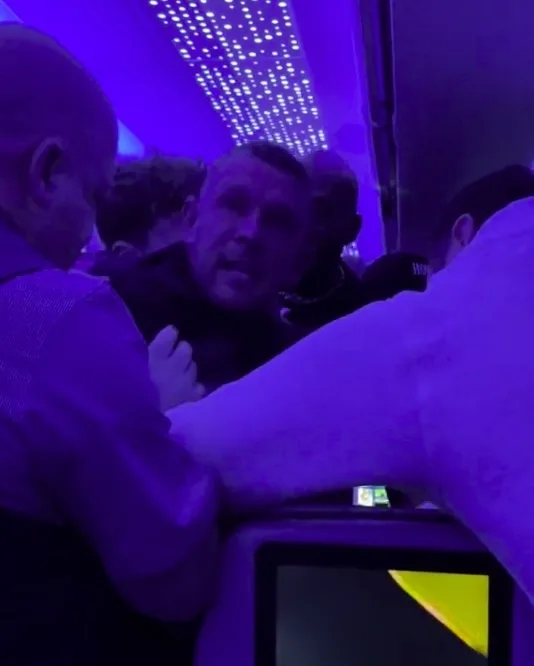 a plane passenger being detained by four fellow Brits men after getting drunk and abusive to cabin crew on the JetBlue flight from Gatwick Airport to New York JFK.