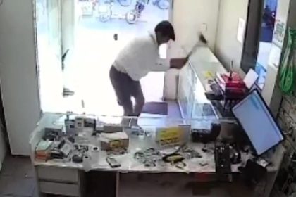 An angry customer wrecked a Brazilian phone shop with a sledgehammer over a £25 repair bill, endangering a worker and his child. The suspect is now missing, police report.