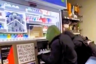 Masked thieves loot a Tesco Express in front of stunned shoppers, stealing cigarettes and spirits. The brazen theft was caught on camera, leaving the public shocked and outraged.