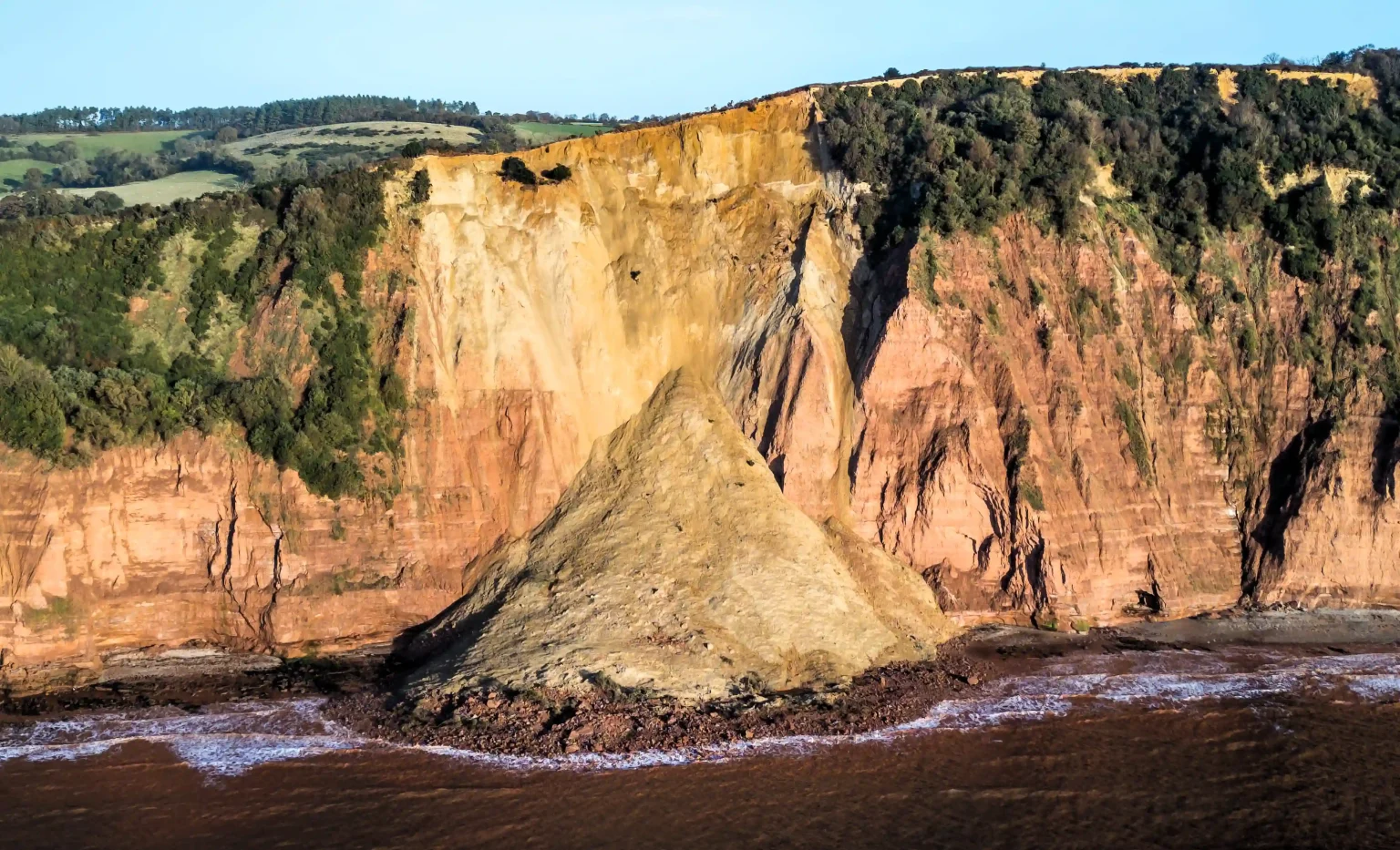 Warning issued after massive cliff collapse in Sidmouth, Devon, closing coastal path. Beach-goers advised to stay clear due to risk of further rock falls.