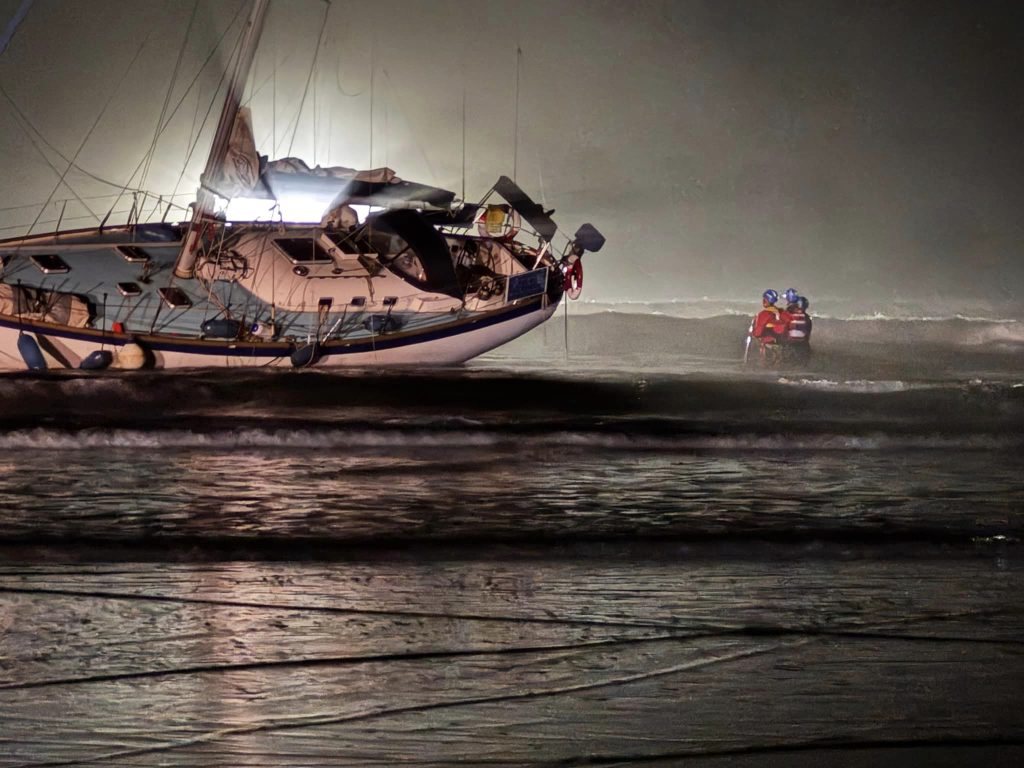 Yacht runs aground on Polzeath beach, Cornwall, after skipper's reported ‘wrong turn’; coastguard and lifeboats assist as onlookers watch from a safe distance.
