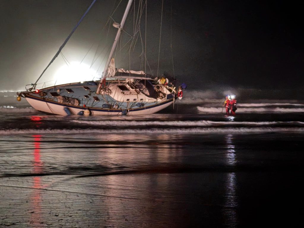 Yacht runs aground on Polzeath beach, Cornwall, after skipper's reported ‘wrong turn’; coastguard and lifeboats assist as onlookers watch from a safe distance.