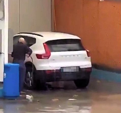 A car owner in storm-hit Malaga cleans his SUV amid torrential rain and winds from Dana, sparking bewilderment as severe weather wreaks havoc across Costa del Sol.