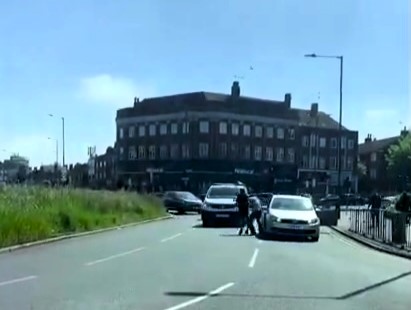 Two drivers brought traffic to a halt in a Wrestlemania-style road rage brawl at Kingsbury Circle, London, trading punches in a dramatic fistfight caught on camera.