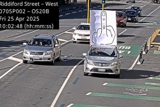 A man sparked viral laughs after driving in a New Zealand bus lane with a giant middle finger sign on his car roof, seemingly aimed at speed cameras.