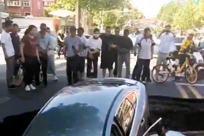 Two cars plunge into a giant sinkhole on a busy Handan road in China - dramatic CCTV shows one car falling and another landing on top as traffic halts in shock.