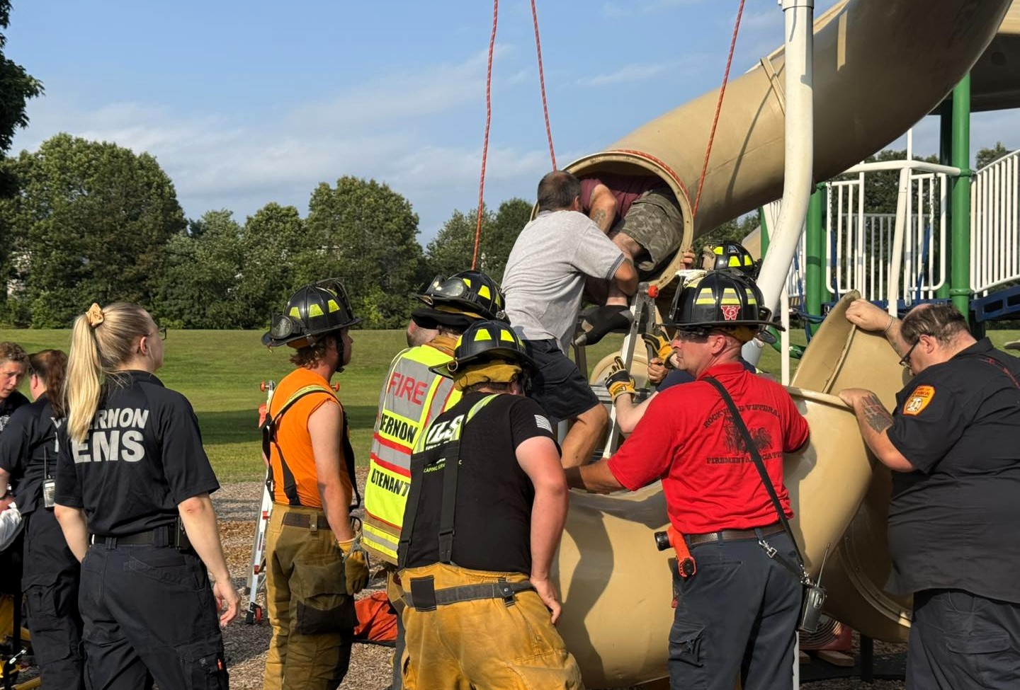 Man trapped in children’s playground slide cut free by firefighters in sweltering heat dome at a Connecticut school - rescue leaves slide destroyed just before term.