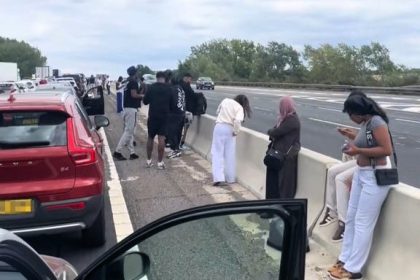 Festival goers set up camp on M1 fast lane after crash caused two hour standstill - drivers spotted playing football as traffic froze near Milton Keynes.