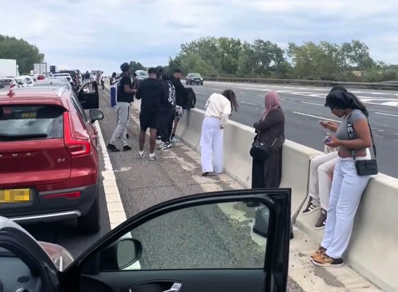 Festival goers set up camp on M1 fast lane after crash caused two hour standstill - drivers spotted playing football as traffic froze near Milton Keynes.