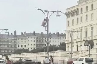 A man was filmed climbing 50 lampposts to rip down Union flags in Brighton as crowds cheered and car horns blared - the stunt has divided opinion online after going viral.