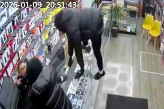 Armed robbers wrestle phone shop worker to floor in Leeds raid - CCTV shows hooded men jump counter with weapons attempting to steal phones, flee empty-handed after brave fight.
