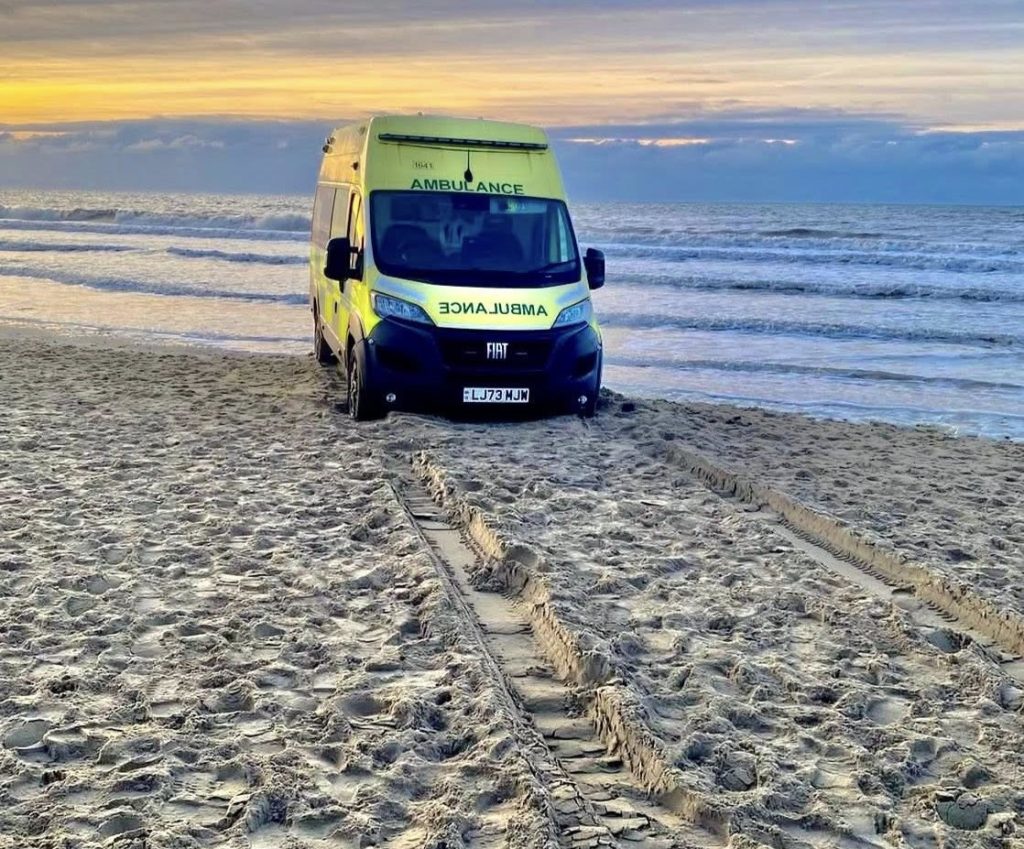 Ambulance with patient inside trapped by rising tide at Camber Sands beach on New Year's Day required off-road recovery vehicle rescue as waves reached its wheels.