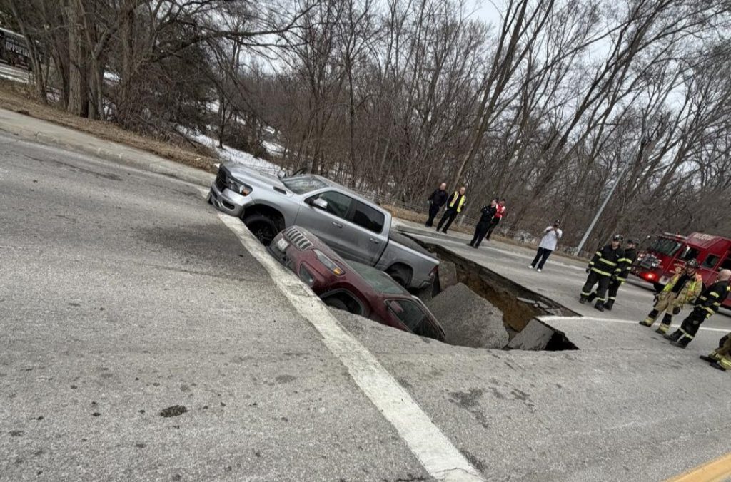 Two cars swallowed by horror sinkhole after road collapses in Omaha - drivers forced to climb out of deep shaft as SUV nearly disappears into the ground.