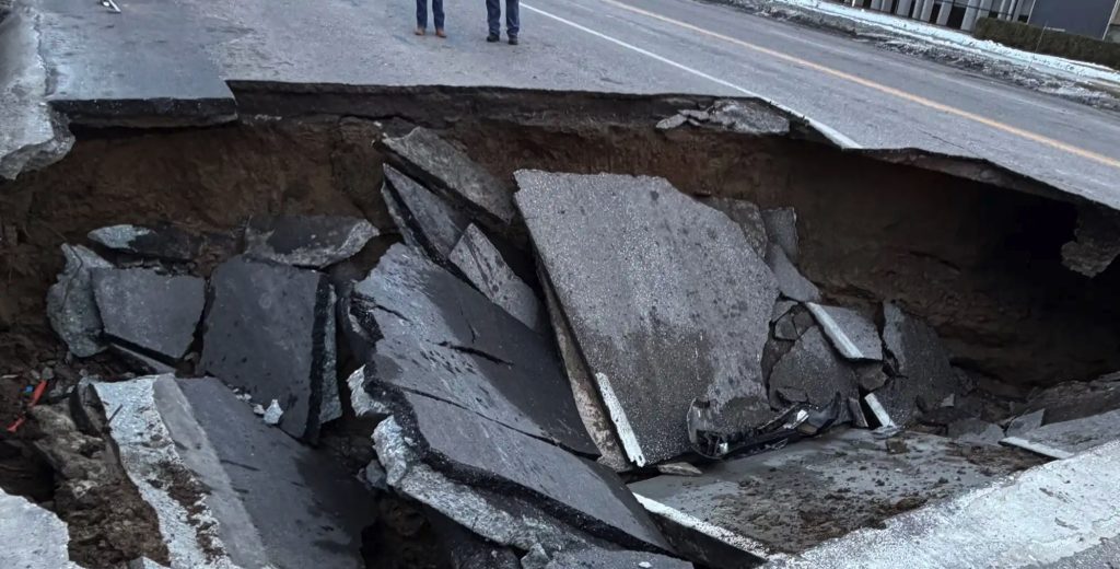 Two cars swallowed by horror sinkhole after road collapses in Omaha - drivers forced to climb out of deep shaft as SUV nearly disappears into the ground.