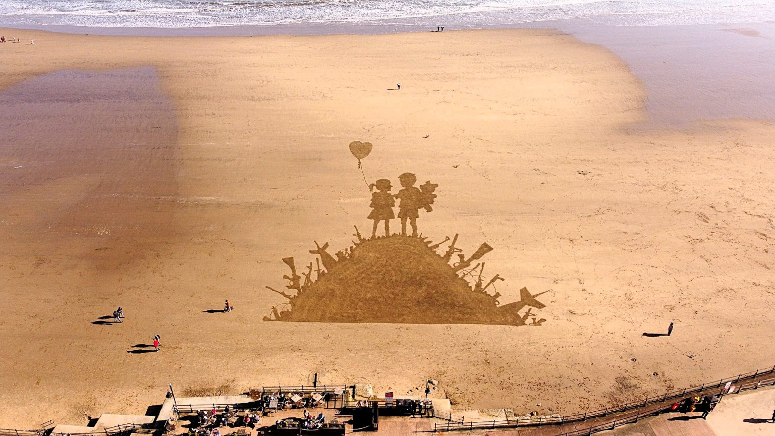 Artist Fred Brown recreates Banksy's iconic Kids on Guns artwork on Scarborough beach using just a rake - a powerful tribute amid global conflict that stunned visitors.