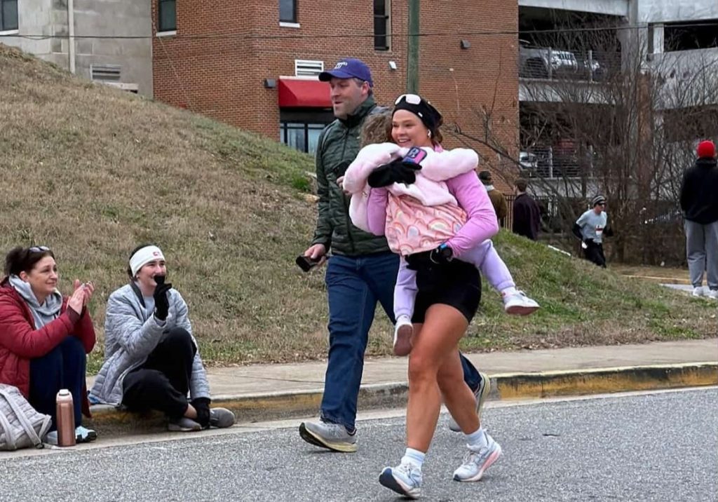 A woman woke up with tingling toes and was paralysed within days by a rare condition - now she has run a marathon and crossed the finish line with her daughter in her arms.
