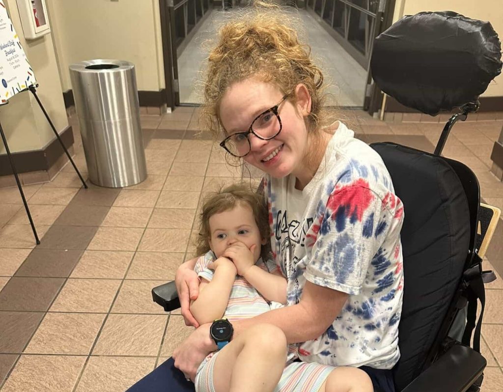 A woman woke up with tingling toes and was paralysed within days by a rare condition - now she has run a marathon and crossed the finish line with her daughter in her arms.