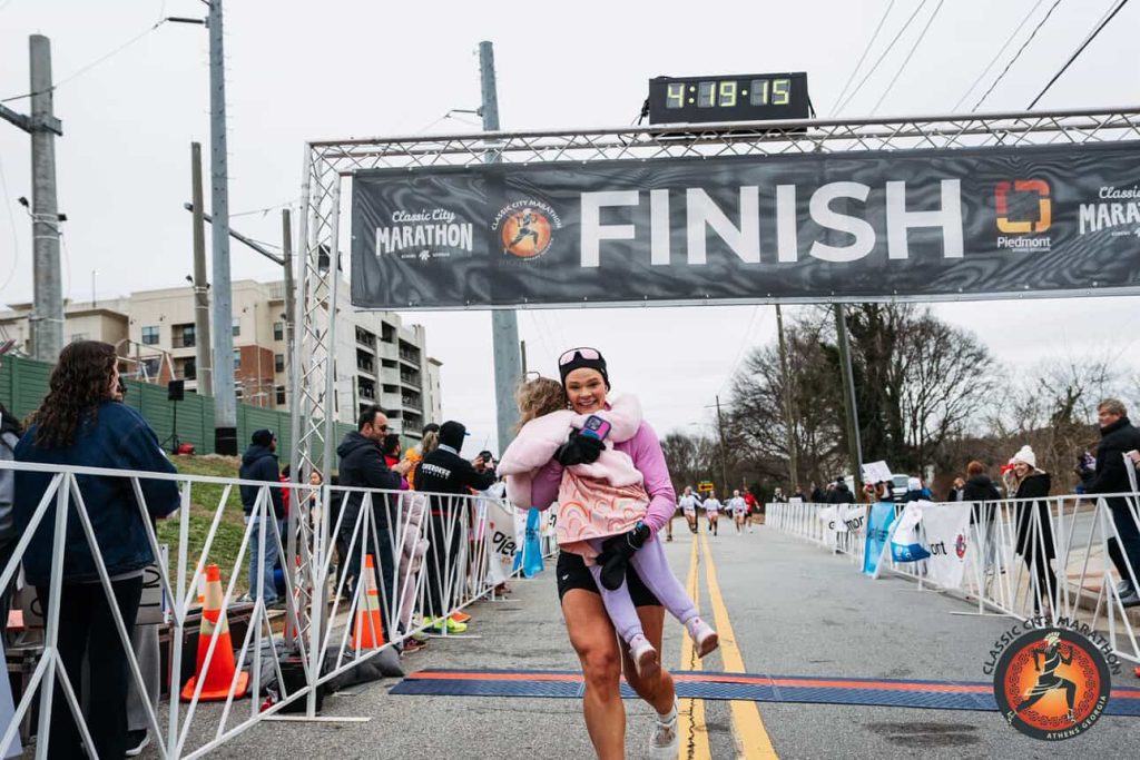 A woman woke up with tingling toes and was paralysed within days by a rare condition - now she has run a marathon and crossed the finish line with her daughter in her arms.