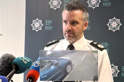 A car bomb exploded yards from a police officer outside a Belfast station after a delivery driver was forced at gunpoint to transport the device, with families narrowly escaping injury.
