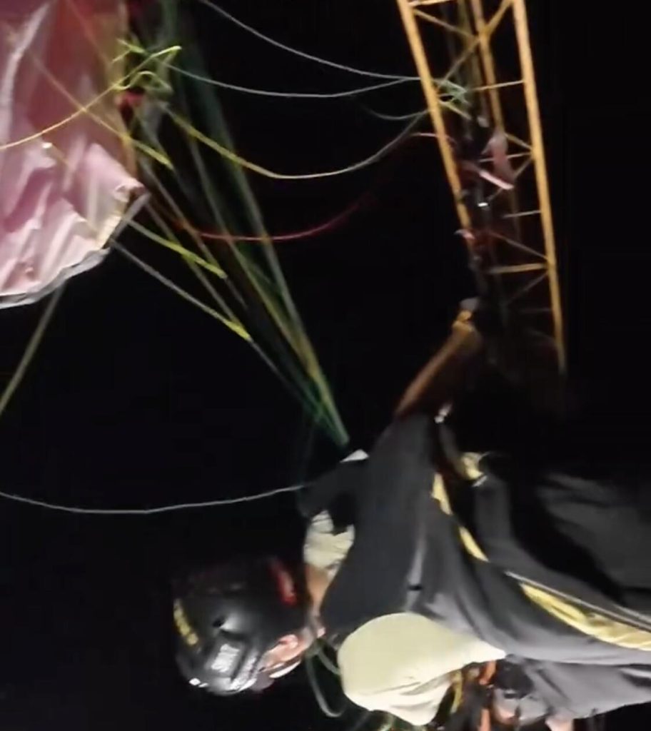 A paraglider was left dangling from a 197ft construction crane after his lines became tangled in the structure - firefighters spent hours cutting him free in a night-time rescue operation.