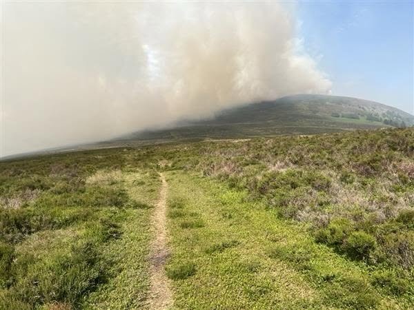 Britain's record-breaking June heatwave sparked a huge wildfire on Derbyshire moorland, sending a massive plume of smoke billowing for miles as crews and a helicopter battled the blaze.