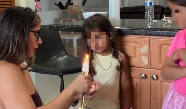 A mum has been arrested after videos allegedly showed her pouring melted candle wax onto her young daughters and setting fire to clothing inside their home.