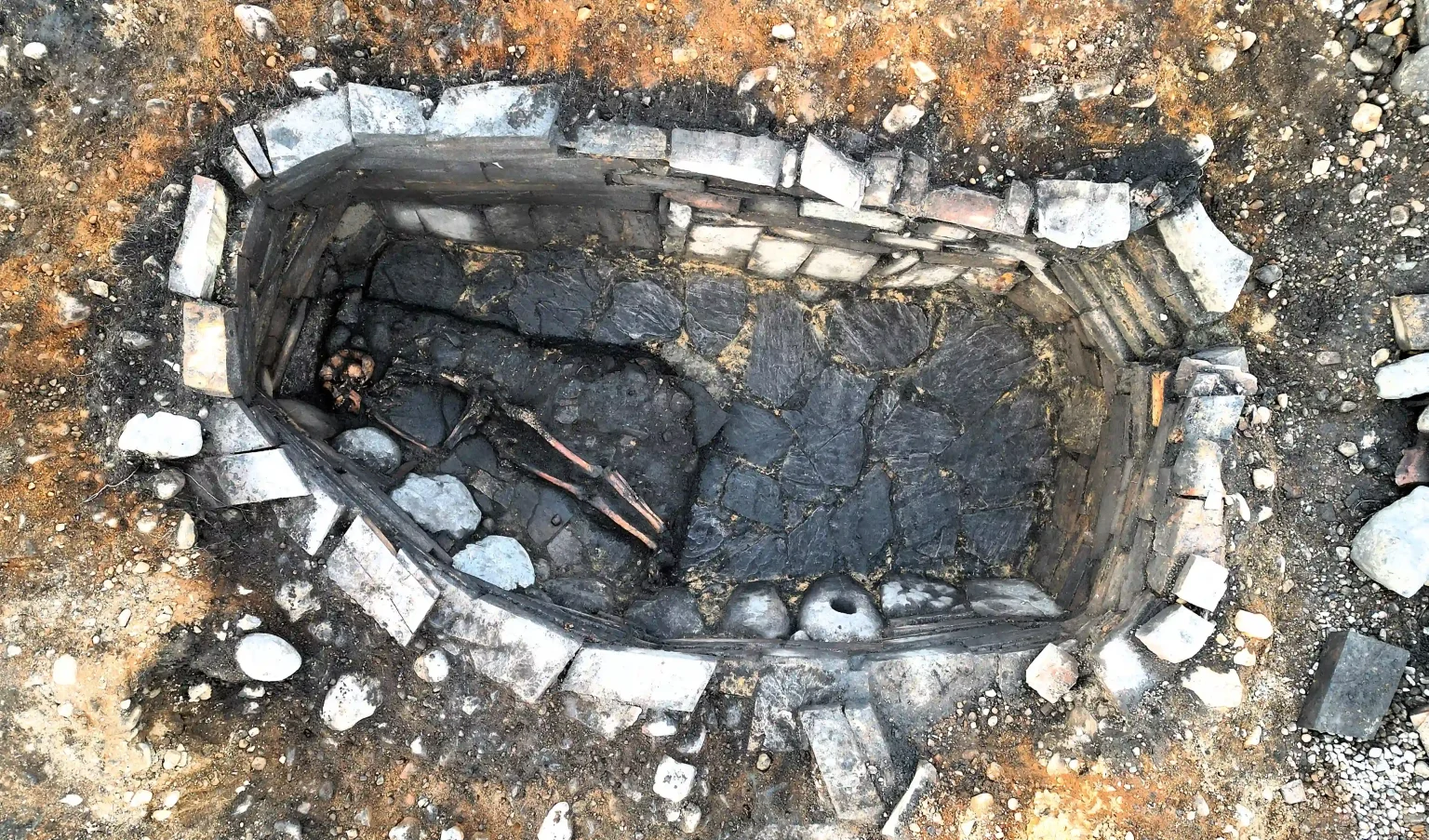 Archaeologists have unearthed a mysterious 2,000-year-old Iron Age pit holding a woman's skeleton - with one expert joking it could have been an ancient hot tub.