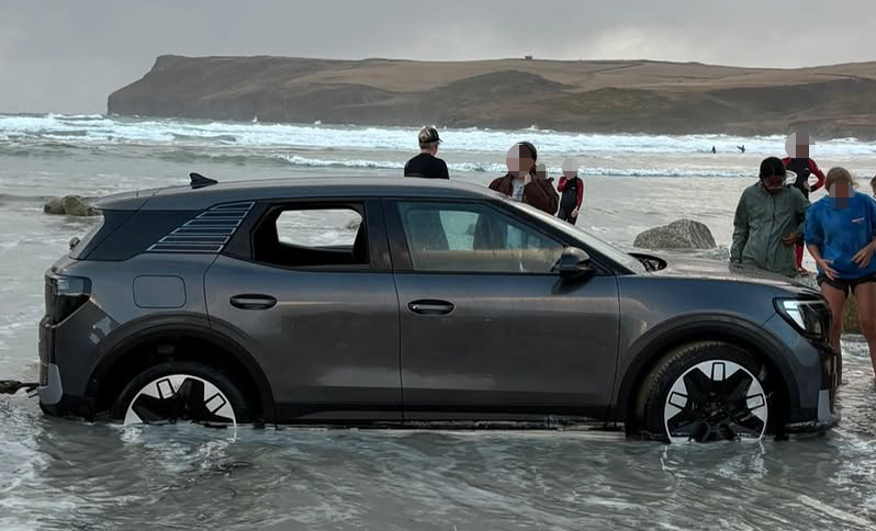 A car was left stranded on a Cornish beach with its wheels buried in sand as the tide crept in - and onlookers joked it should be put in a bowl of rice.