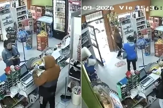 A hooded thief stopped mid-robbery to serve a customer - scanning her shopping, taking payment and handing over a receipt while a worker was locked in the toilet.