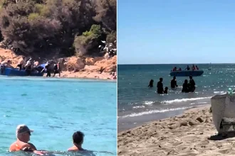 A migrant boat was filmed racing towards a packed Sardinian beach - before furious beachgoers confronted the boatman and forced the vessel to turn around.