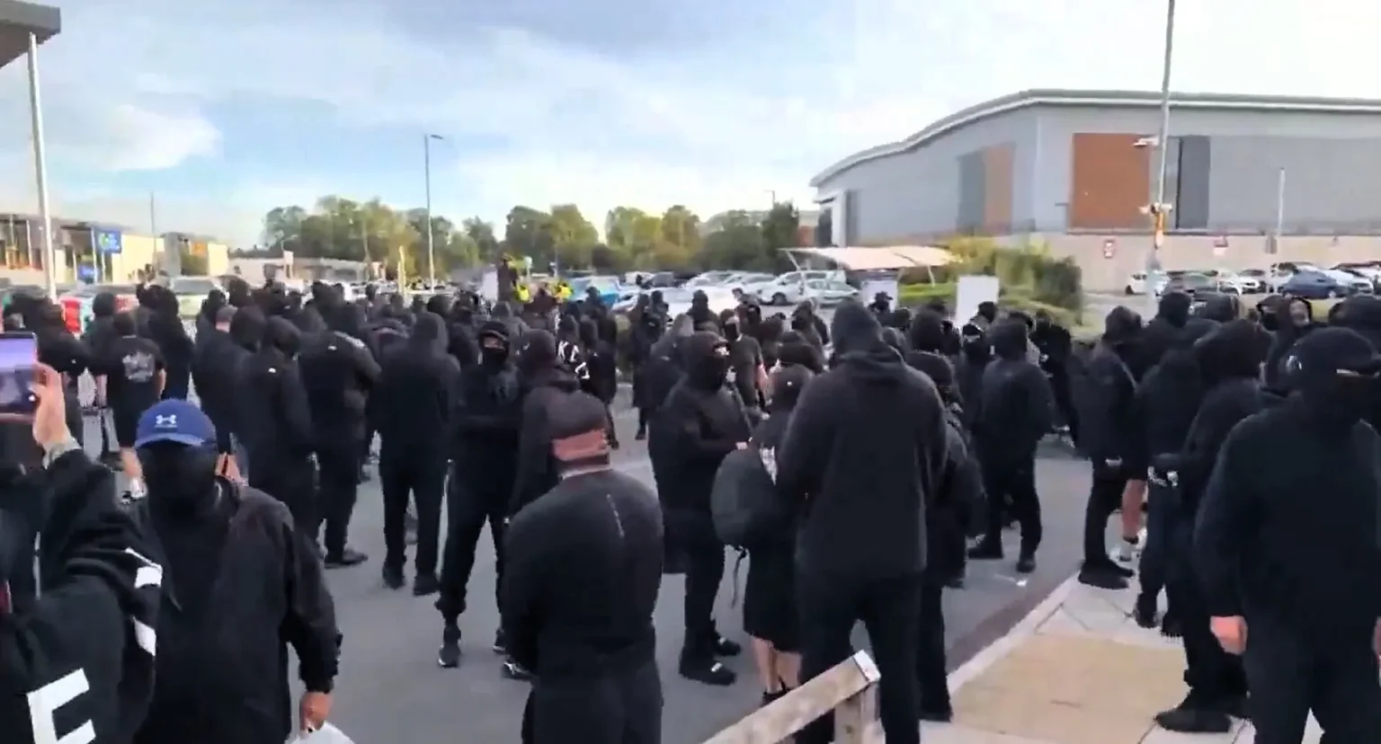 Hundreds of masked supporters faced off with police outside Basingstoke Police Station after anti-migrant activist Danny Tommo was charged over a slashed Channel dinghy.