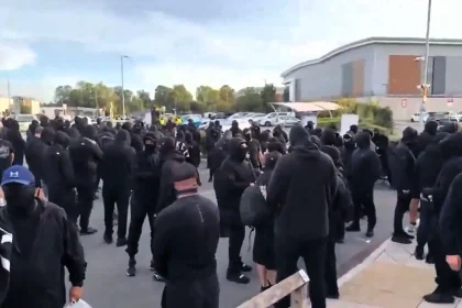 Hundreds of masked supporters faced off with police outside Basingstoke Police Station after anti-migrant activist Danny Tommo was charged over a slashed Channel dinghy.