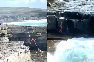 A tourist was rescued after being knocked off a cliff into Ireland's notorious Wormhole blowhole on Inis Mór, with a helicopter crew battling huge waves to reach him.