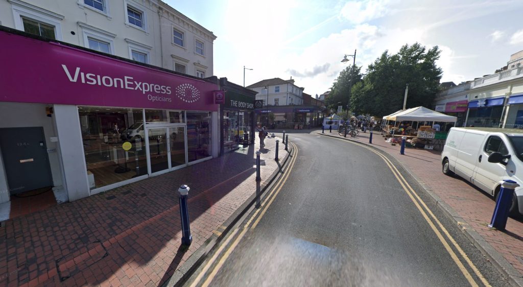 A hooded thief stopped mid-robbery to serve a customer - scanning her shopping, taking payment and handing over a receipt while a worker was locked in the toilet.