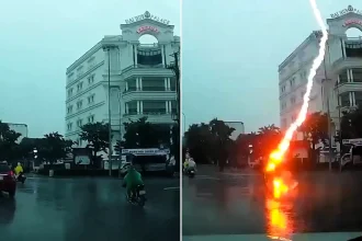Shocking dashcam footage shows the moment a woman was struck by lightning while riding her motorbike through a busy roundabout in Vietnam - and amazingly survived.