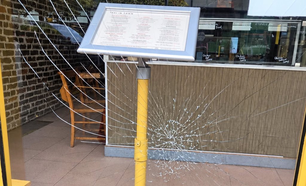 A thug smashed a restaurant's glass door with a single kick in a random attack - leaving the business facing a repair bill of up to £1,000.