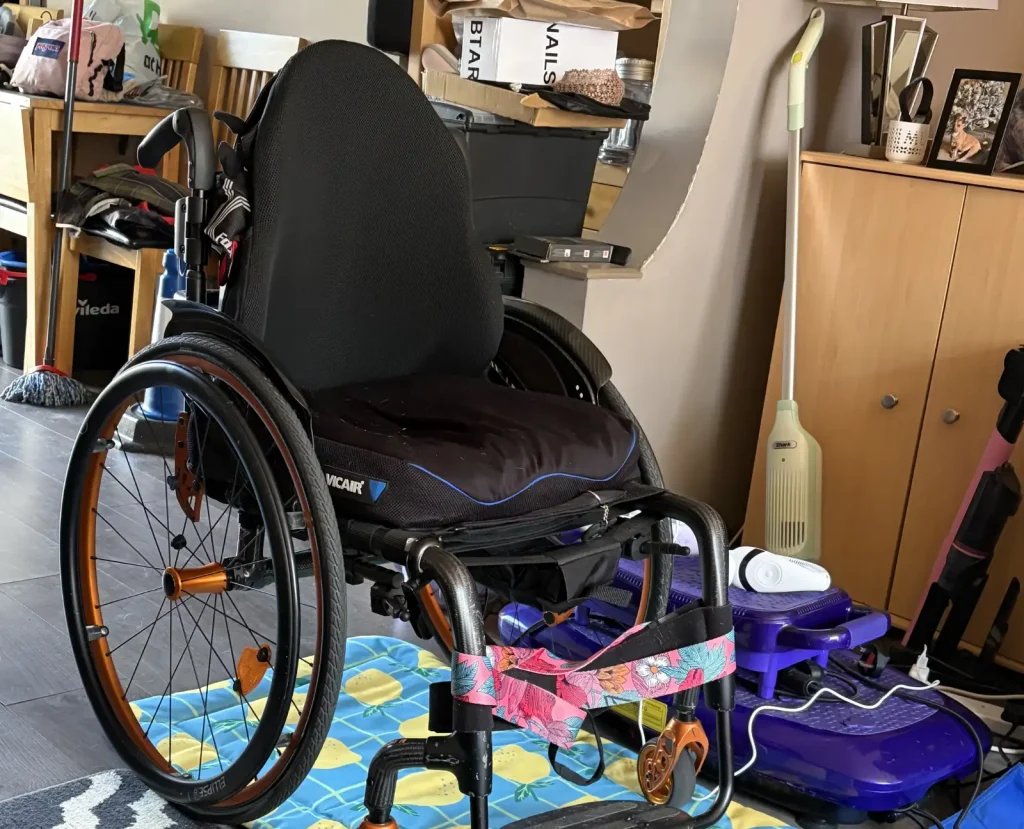 A manual wheelchair with black seat and back shown in detail in a domestic setting.