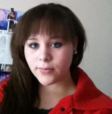 Danielle Dyson, a young woman with dark hair wearing a red top, looking at the camera.