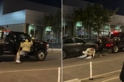 Desperate driver armed with a pool cue clung to his car as a tow truck drove off with it in Chicago. The man fell onto the road during the bizarre incident.