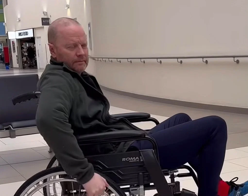 Man in wheelchair in hospital corridor.