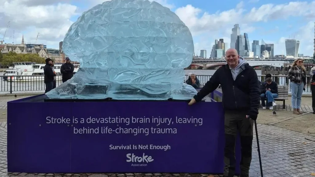 Man standing by large blue head sculpture promoting stroke awareness.