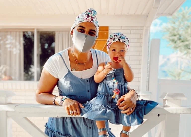 Woman and young girl wearing matching blue outfits and headwear indoors