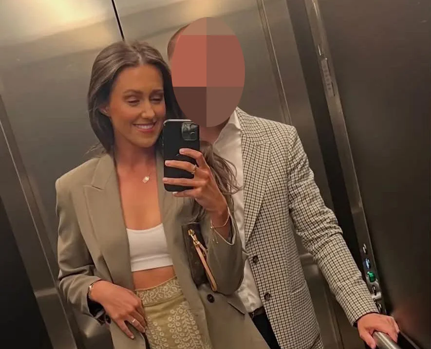 Woman in beige blazer next to man with pixelated face in elevator mirror selfie