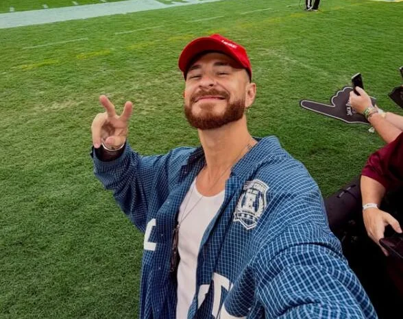 Fred Bruno on a football pitch in a red cap and blue denim shirt, making a peace sign.
